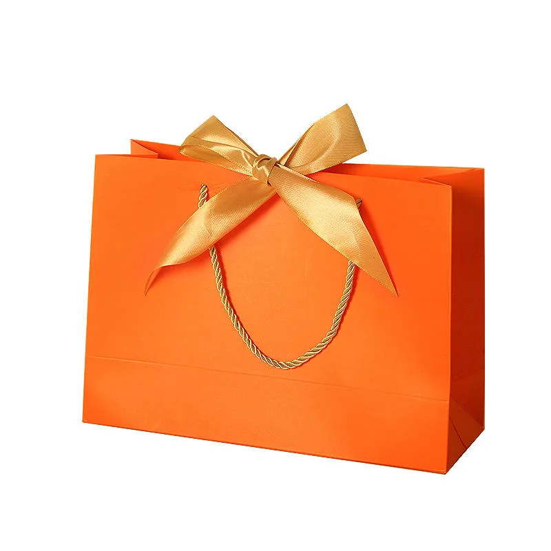Orange shopping paper bag with rope handles and ribbon bow